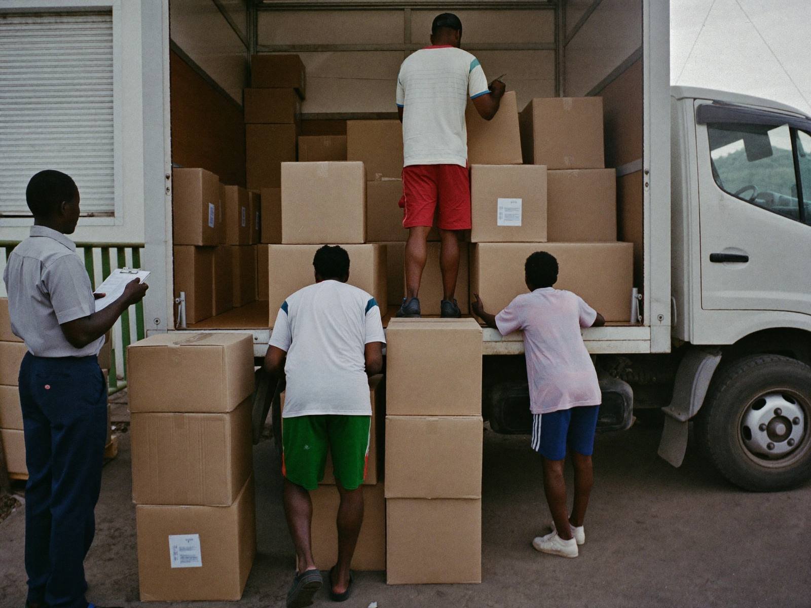 Workers loading boxes onto a truck under supervision
