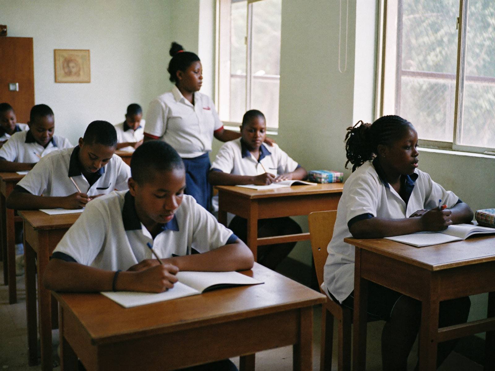 Students writing at desks in a bright classroom